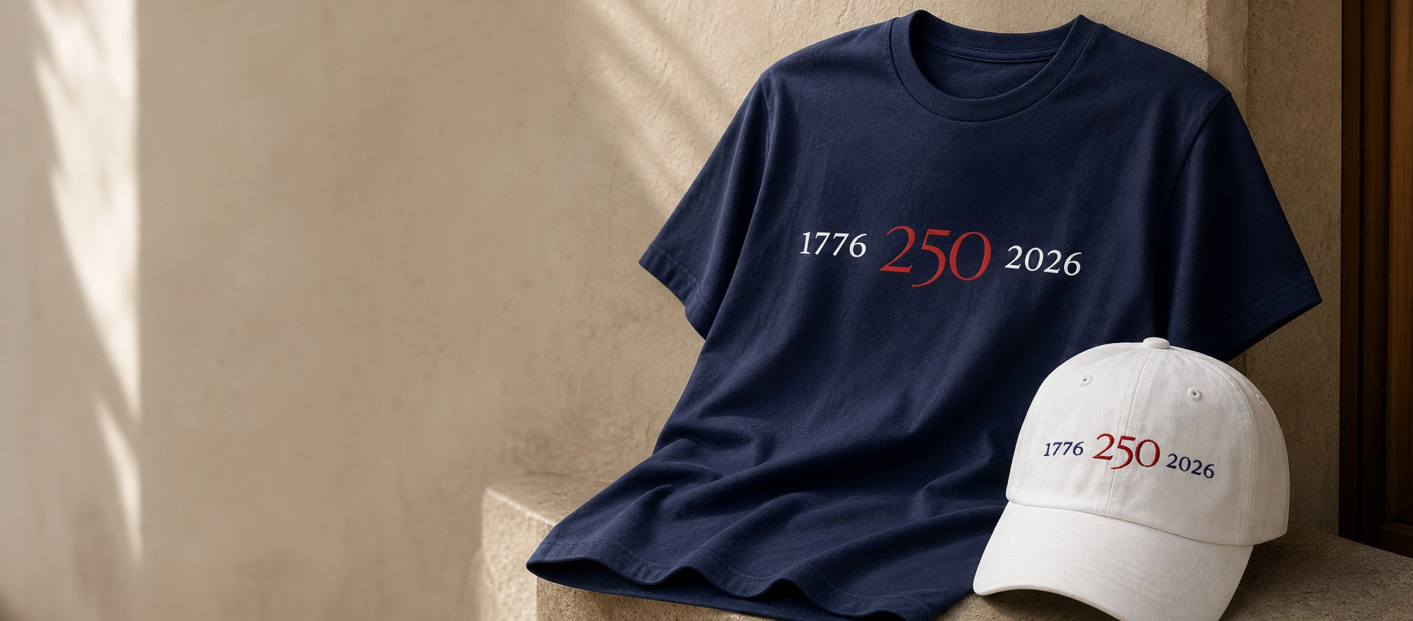 Navy 1776–2026 graphic tee and white embroidered 1776–2026 hat from Atlas Stitch.